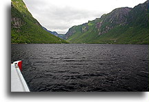Boat in Western Brook Pond::This is a former fjord with granite walls reaching 600 meters (2,000 ft)::